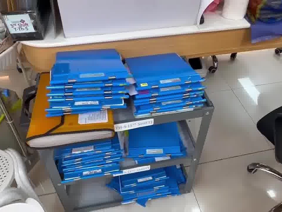 A cart of blue patient-record binders, sorted by shift.